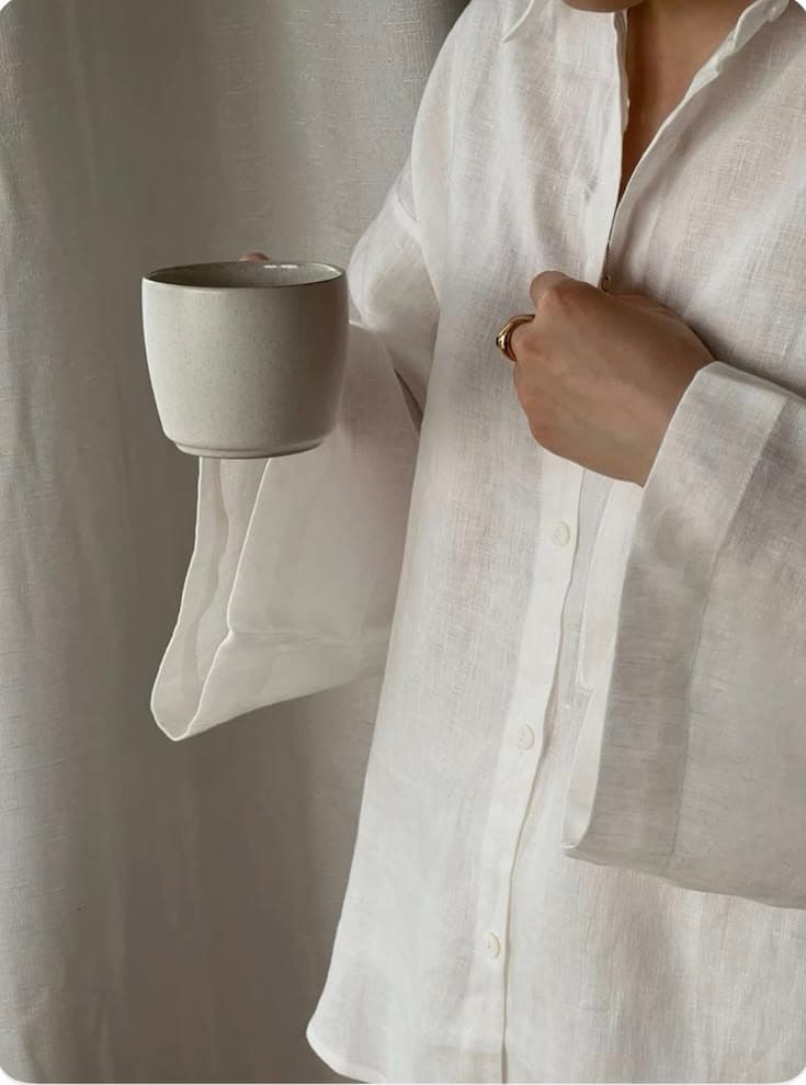 A linen shirt and an unfastened cuff around a warm cup