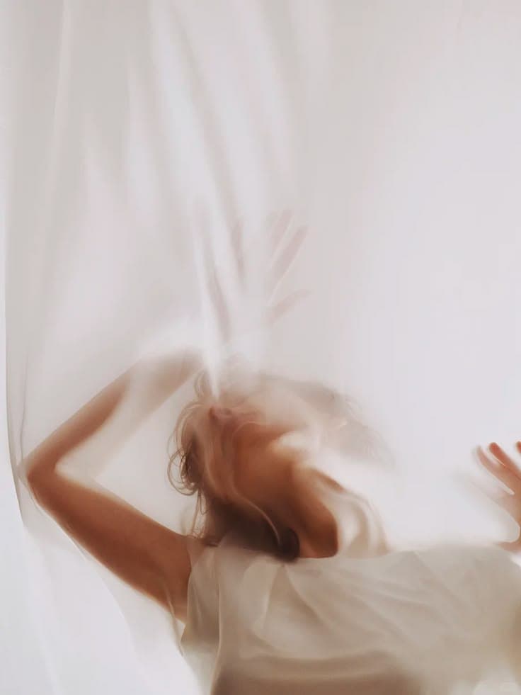 A figure moving behind a sheer length of cloth