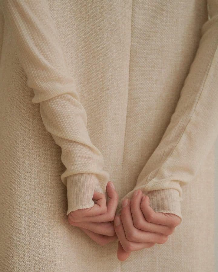Hands folded inside long knitted sleeves