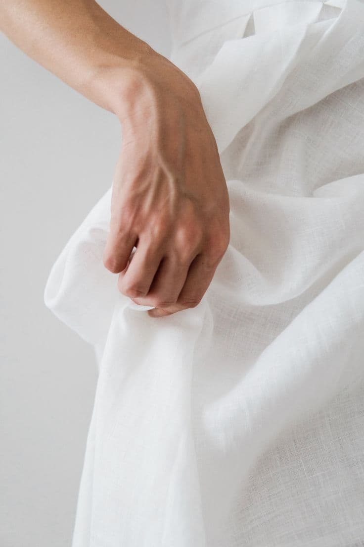 A hand resting on folds of white linen
