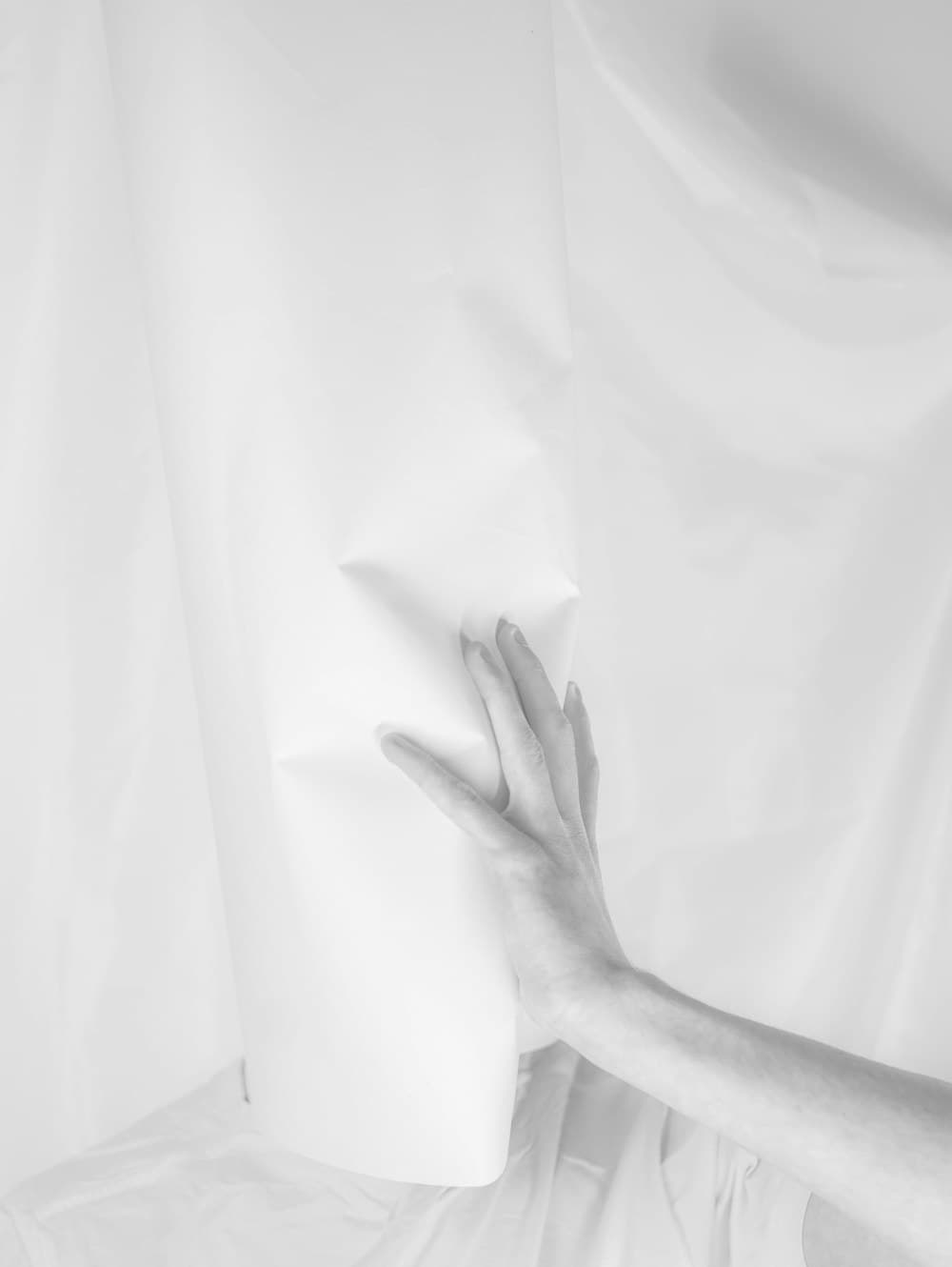 A hand resting behind a sheer length of fabric