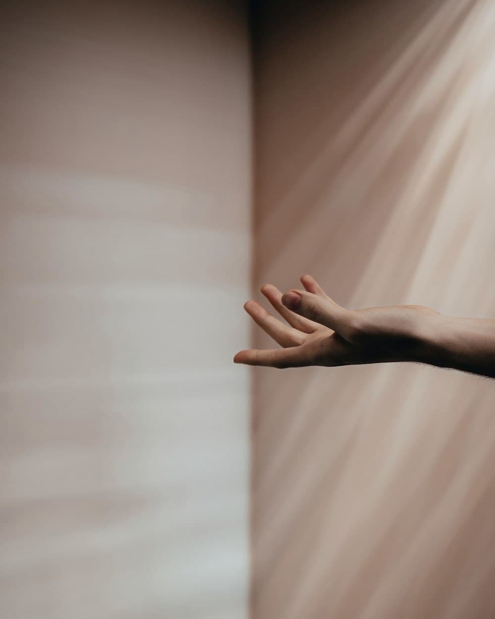 A hand reaching out to feel hanging cloth in daylight